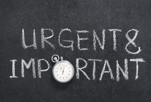 urgent and important phrase handwritten on chalkboard with vintage precise stopwatch used instead of O