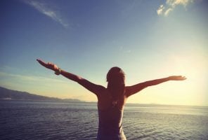 Cheering woman jogger open arms at sunrise seaside,vintage effect