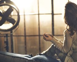 Woman enjoying cup of tea watching the sunset from her window